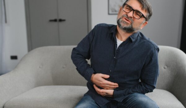 man on sofa holding his chest in pain