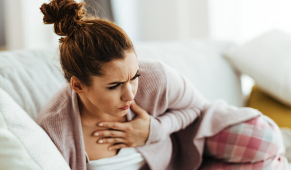 distraught woman holding her chest while lying down on sofa in living room